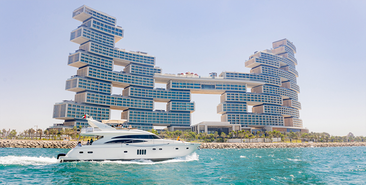 A luxury yacht full of tourists cruising past the waters near Atlantis The Royal in Dubai