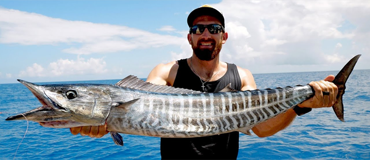 Tourists rentaing a yacht for a fishing trip in Dubai hold up a large fish they have just caught